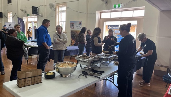 Landholders mill around catering station inside a hall.