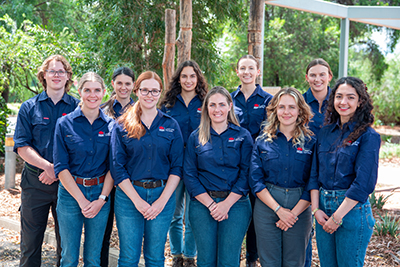 A group of 10 people wearing matching navy shirts and smiling at the camera