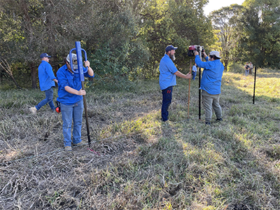 4 men in blue work shirts working in a paddock to install new fences.