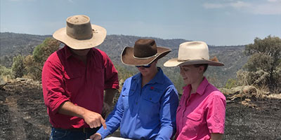 Three people looking at some documents, they look to be talking 