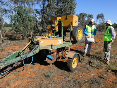 Two men wearing hats standing next to a Direct Seeder