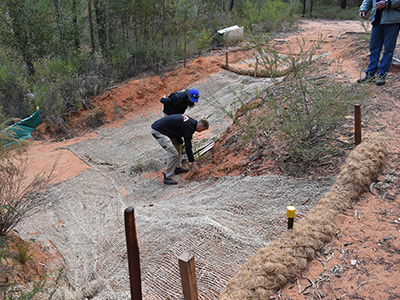 Rangers performing erosion methods on a dirt hill