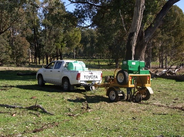 A Toyota ute towing a yellow seeding machine on a paddock
